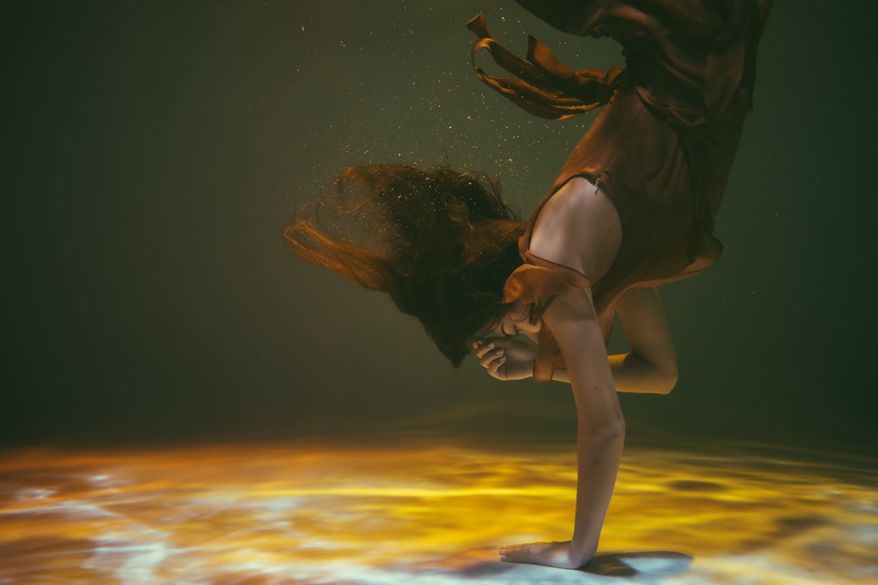 services-02 A woman gracefully poses underwater, enveloped in ethereal light and fluid motion.
