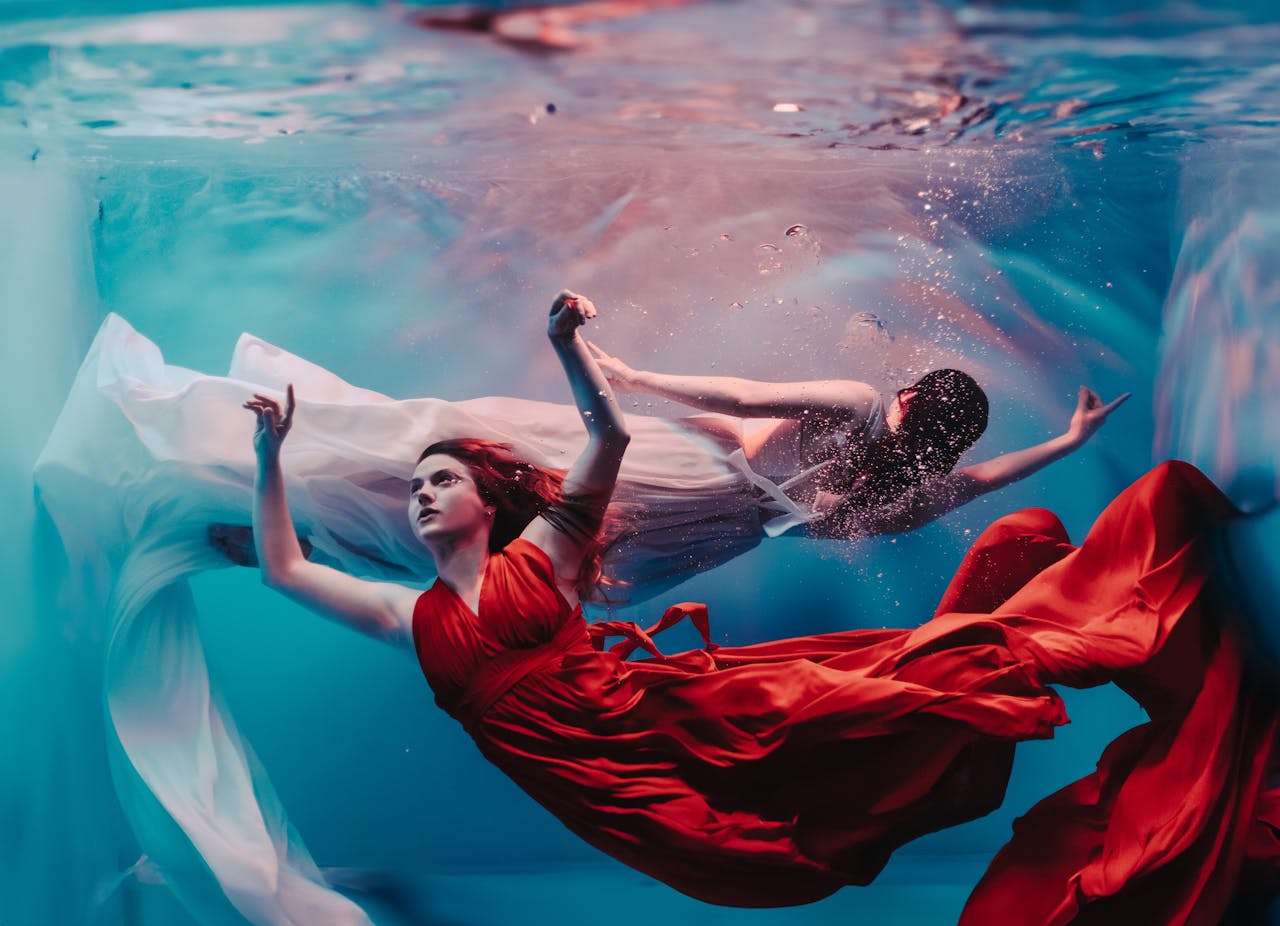 services-03 Artistic underwater scene with models in flowing dresses, creating a surreal fashion moment.