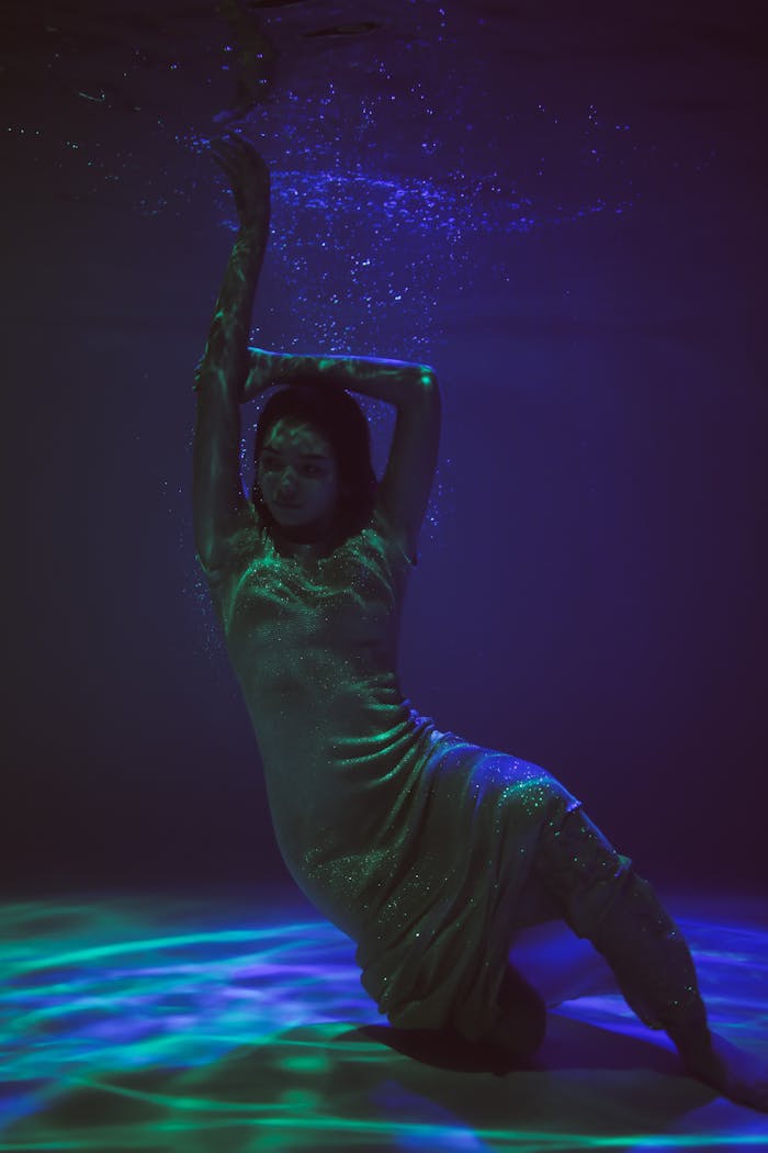 hero-img-02 Artistic underwater photo of a woman posing gracefully with vibrant lighting.